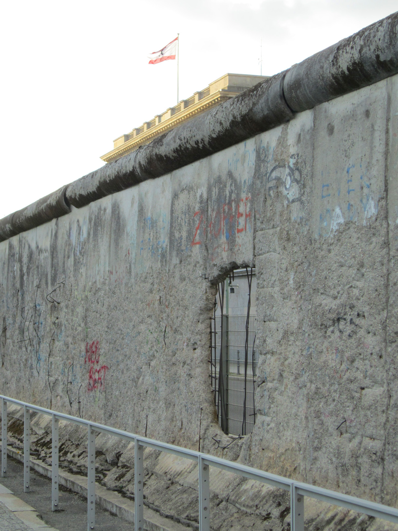 Remains of the Berlin Wall. Berlin’s flag is flying over the parliament building of the city-state